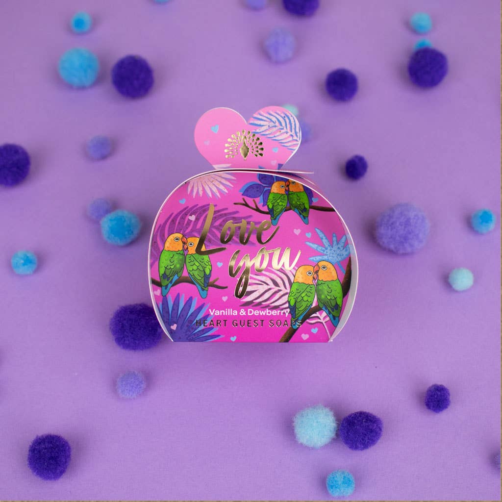 Pink container with parrot design on a purple background with colorful pom-poms