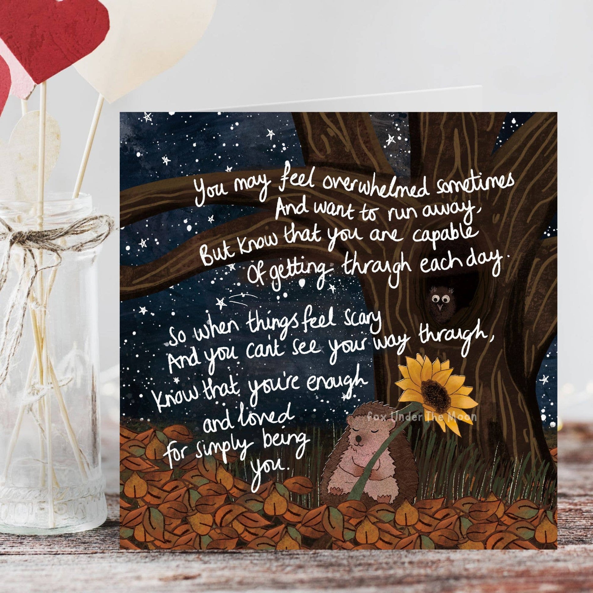 Card with illustration of hedgehog and sunflower with motivational text against a night sky.