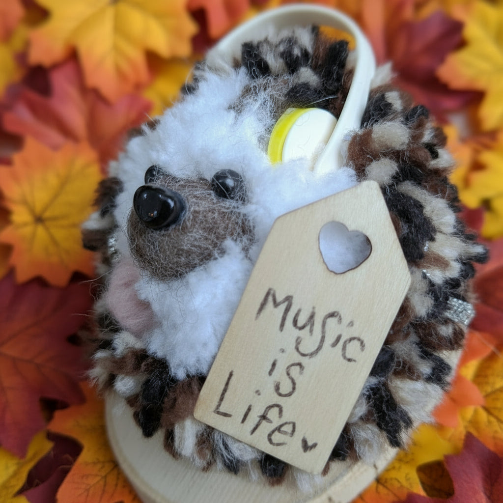 Plush  hedgehog with a 'Music is Life' tag on a wooden surface