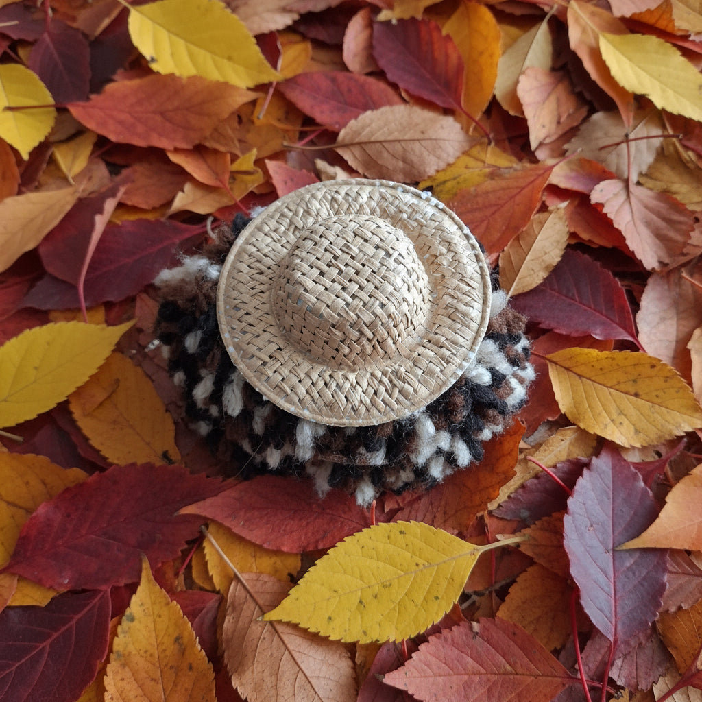 Close-up of a woven hat with a textured band on a wooden surface