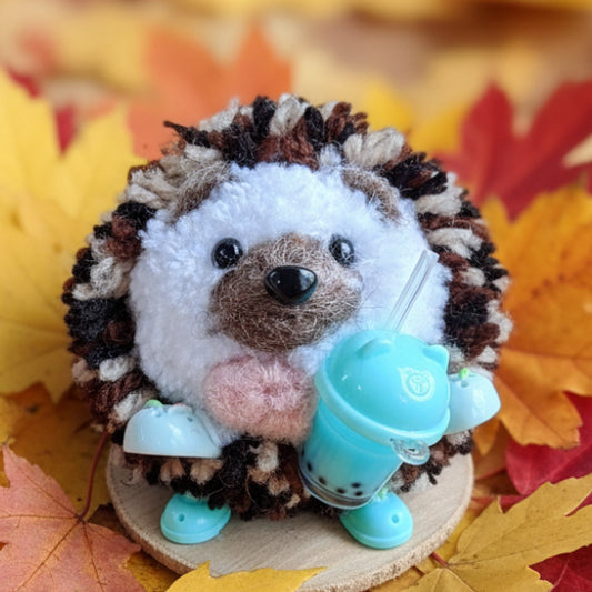 Plush toy hedgehog with a blue bobo tea cup and crocs on a wooden surface