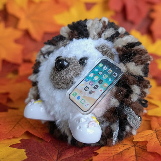 Hedgehog-shaped wollen ornament with a pretend smartphone and crocs