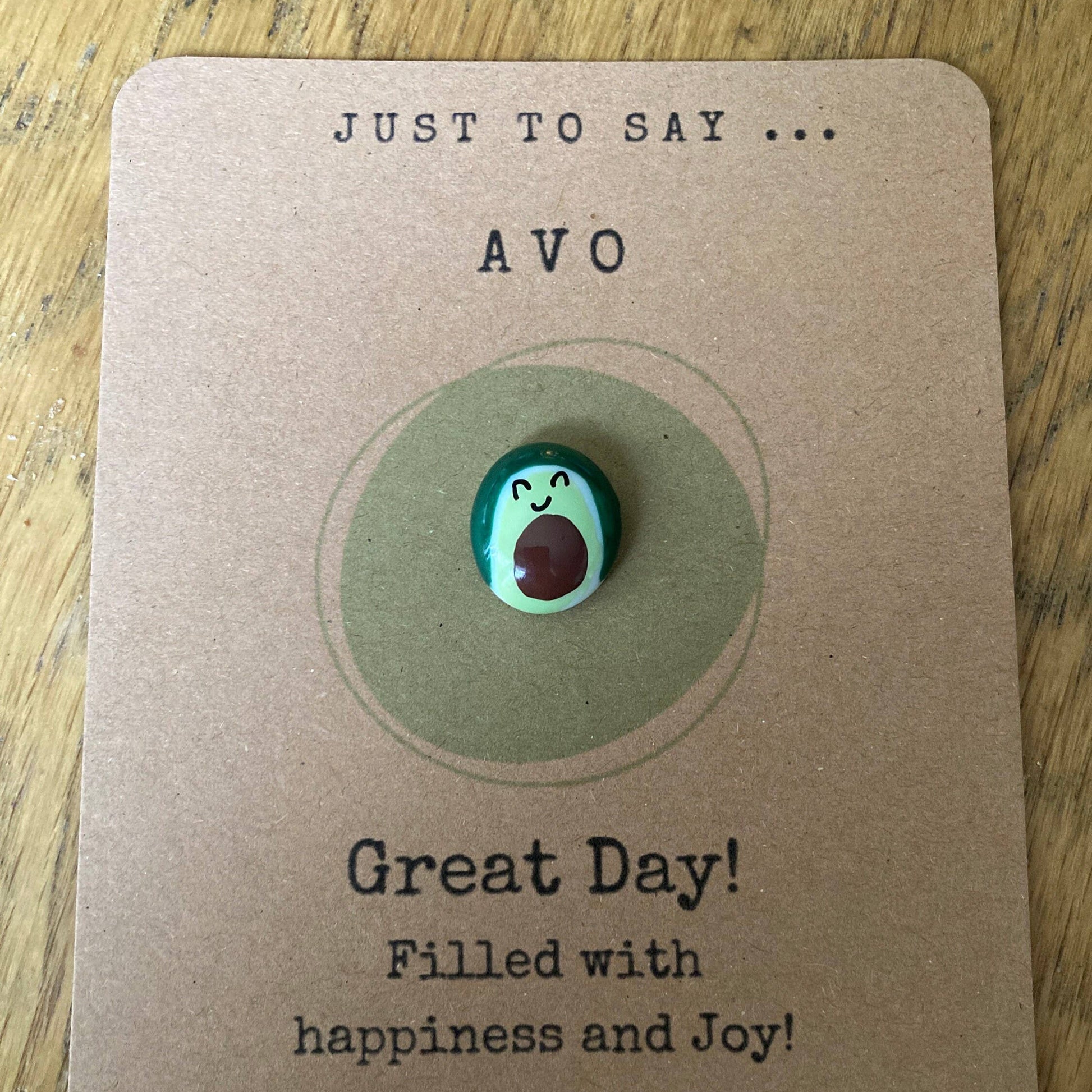 Avocado-shaped charm on a card with text and a website URL.