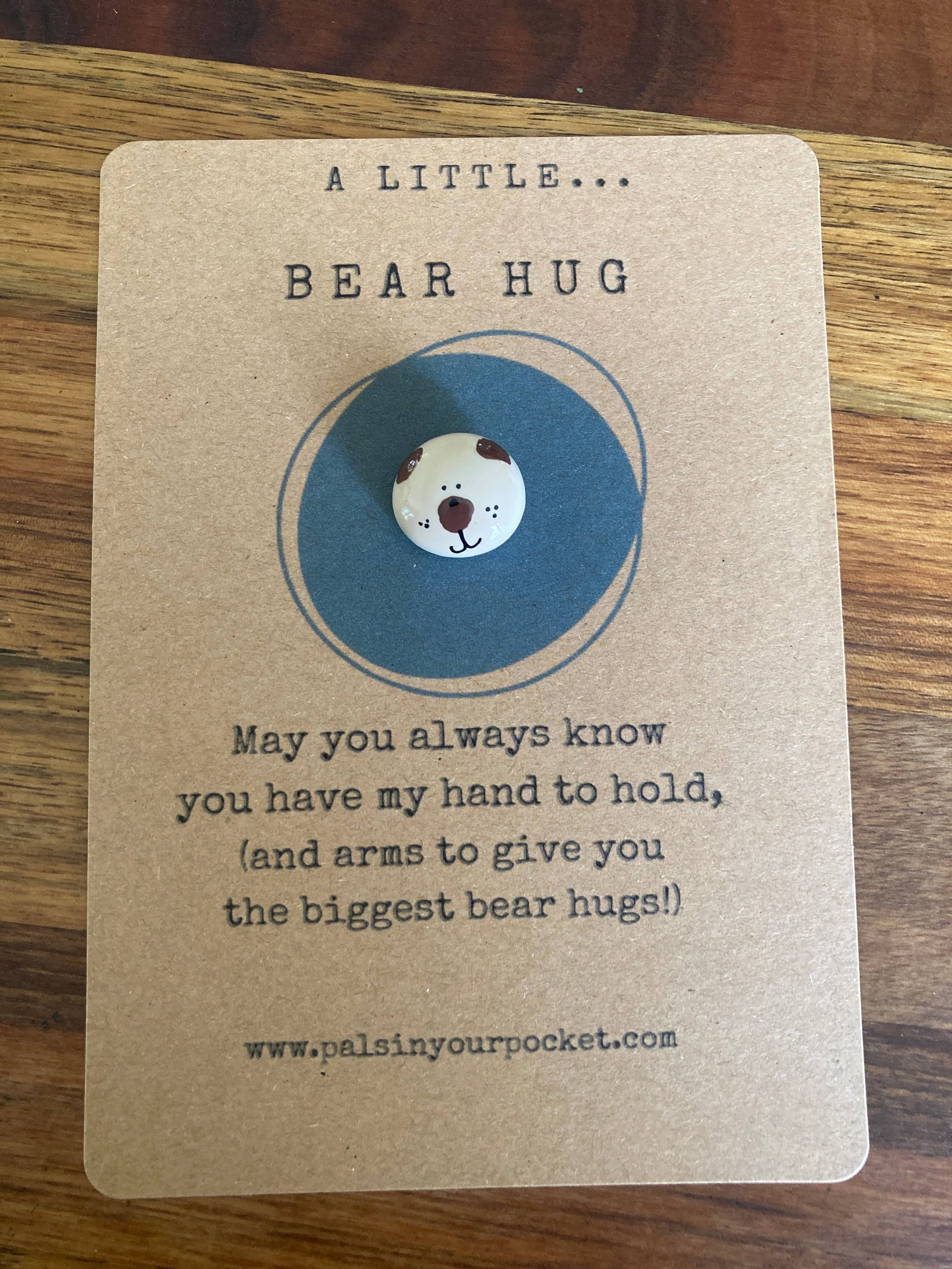Card with a bear charm  and text on a wooden surface