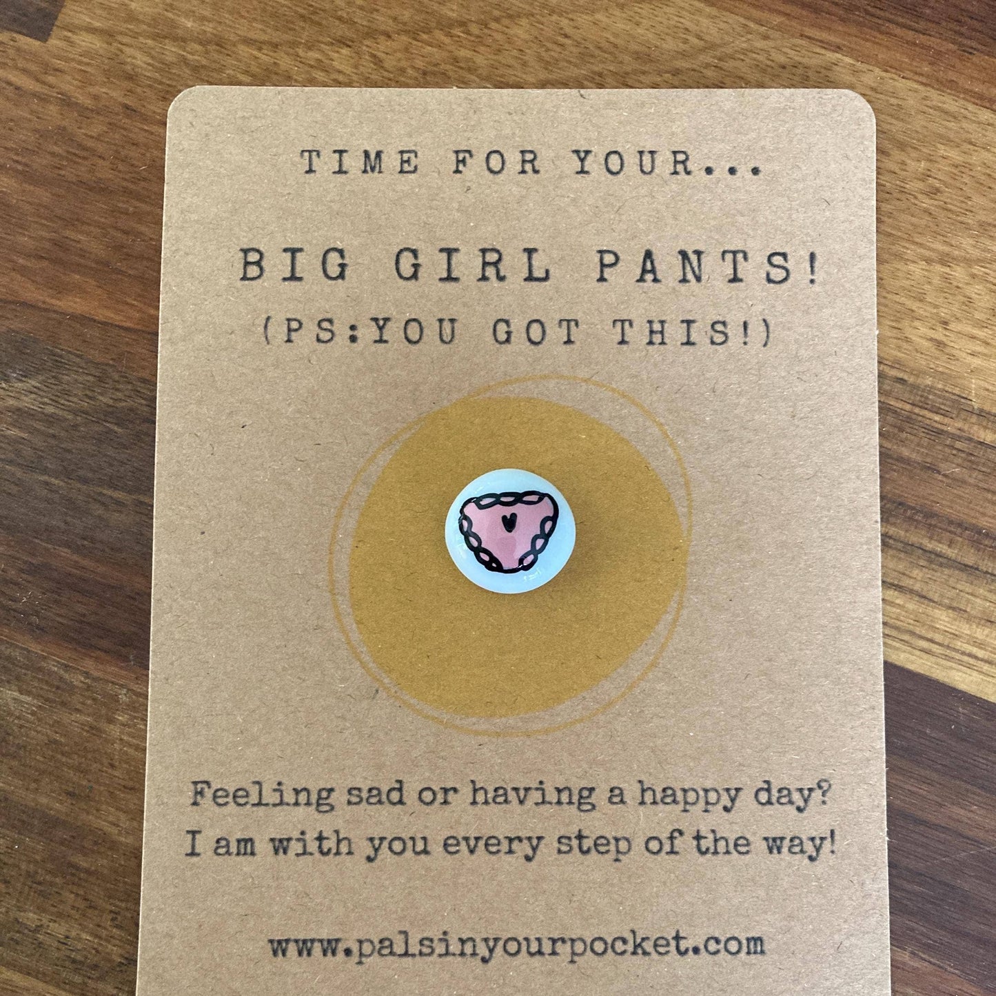 Card with a charm and text on a wooden surface