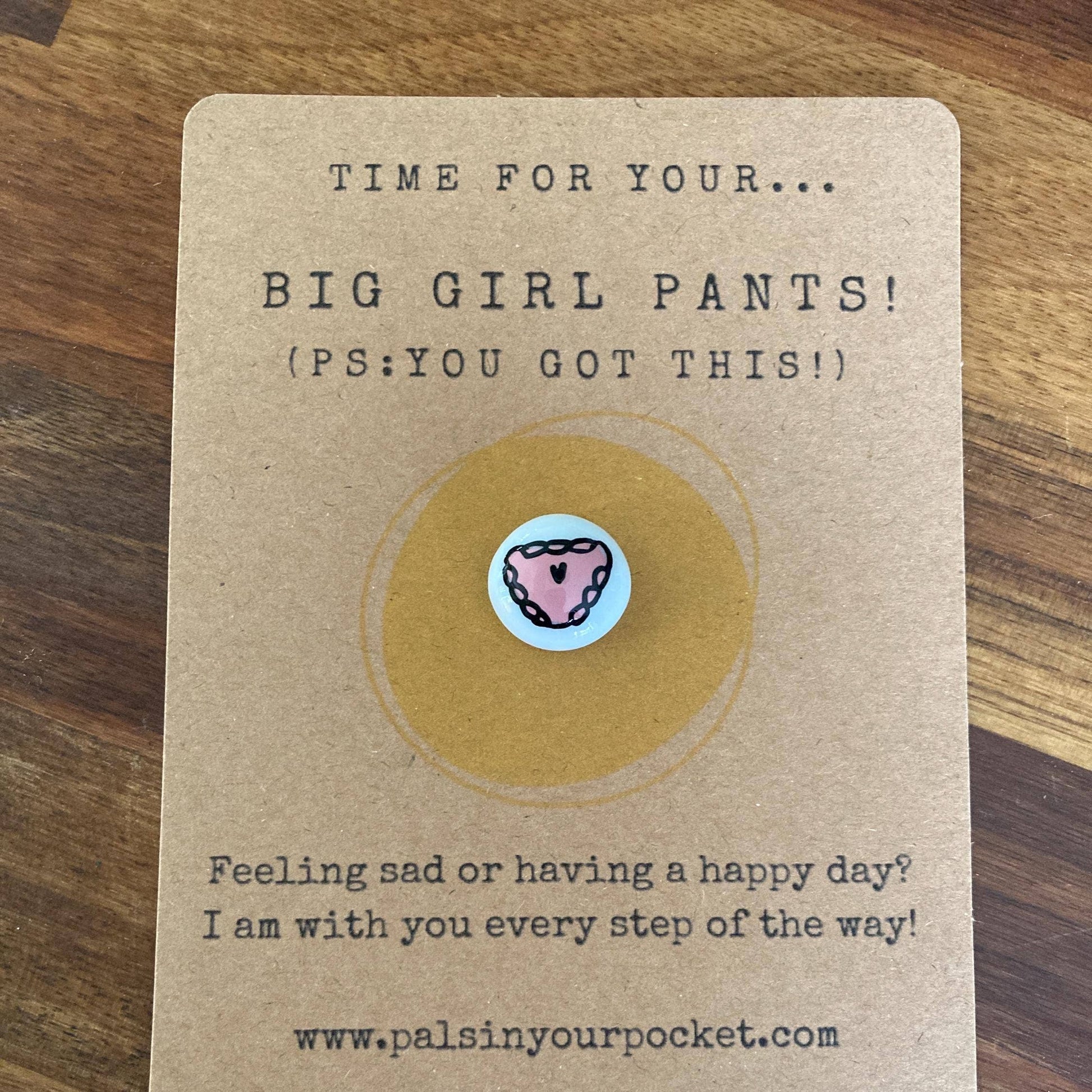 Card with a charm and text on a wooden surface
