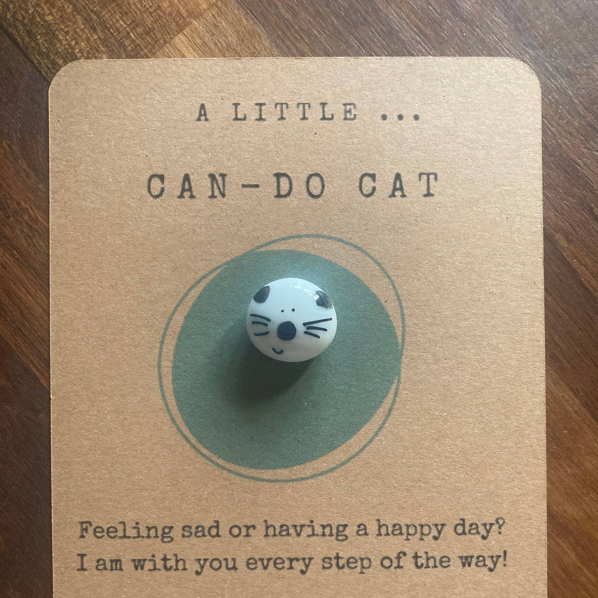 Cat-shaped button on a kraft paper card with text