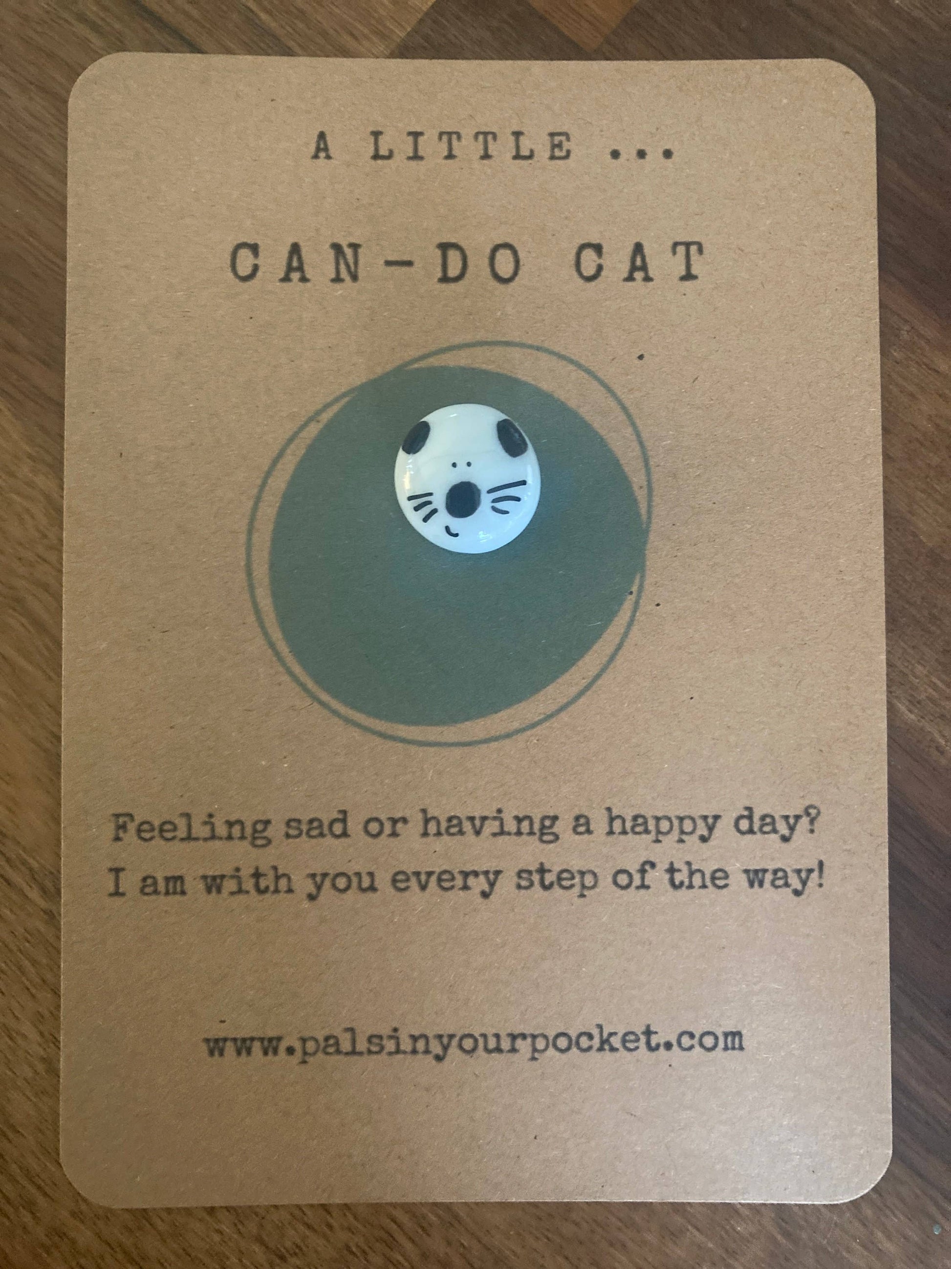 Card with a cat illustration and text on a wooden surface