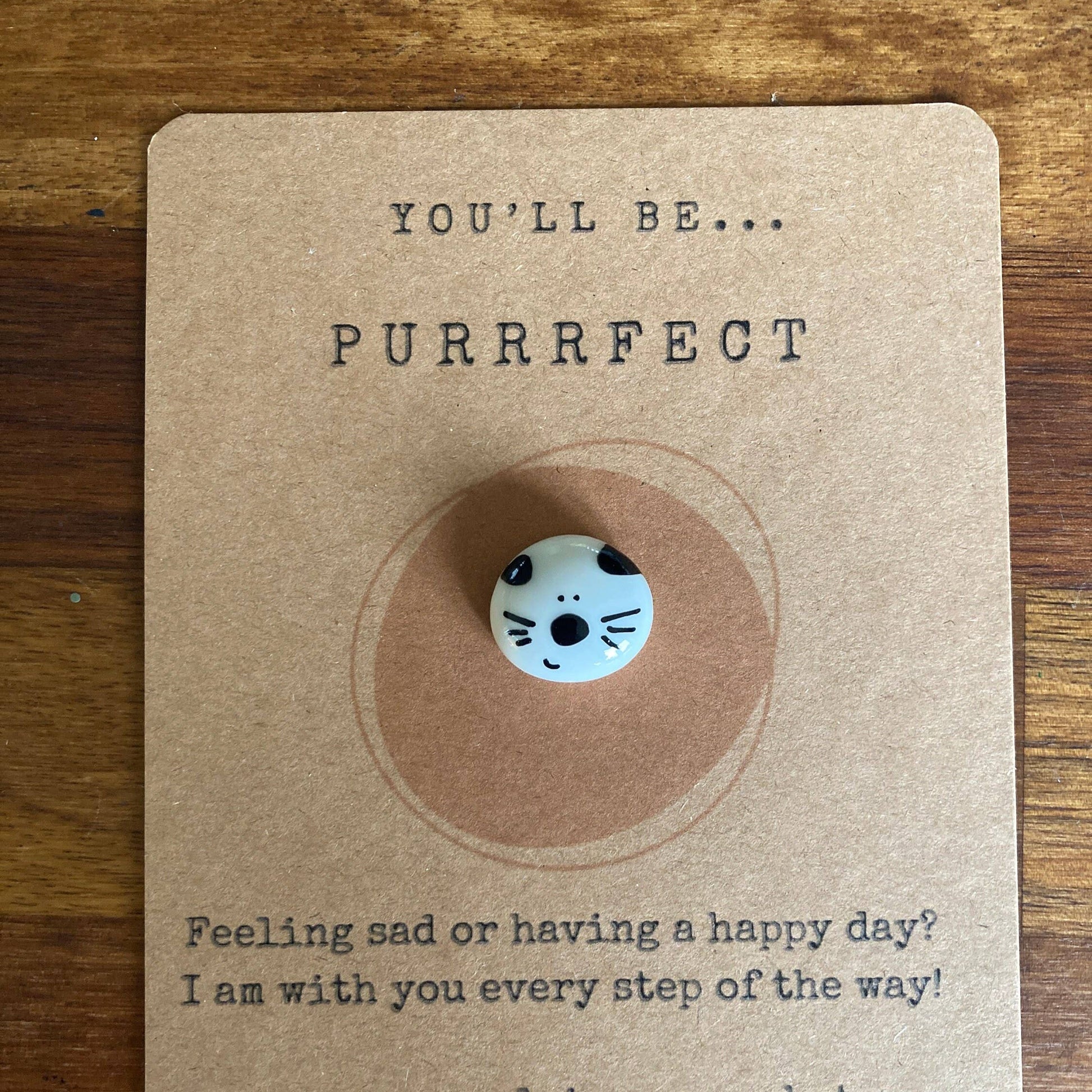 Kraft paper card with a cat-themed token and text on a wooden surface