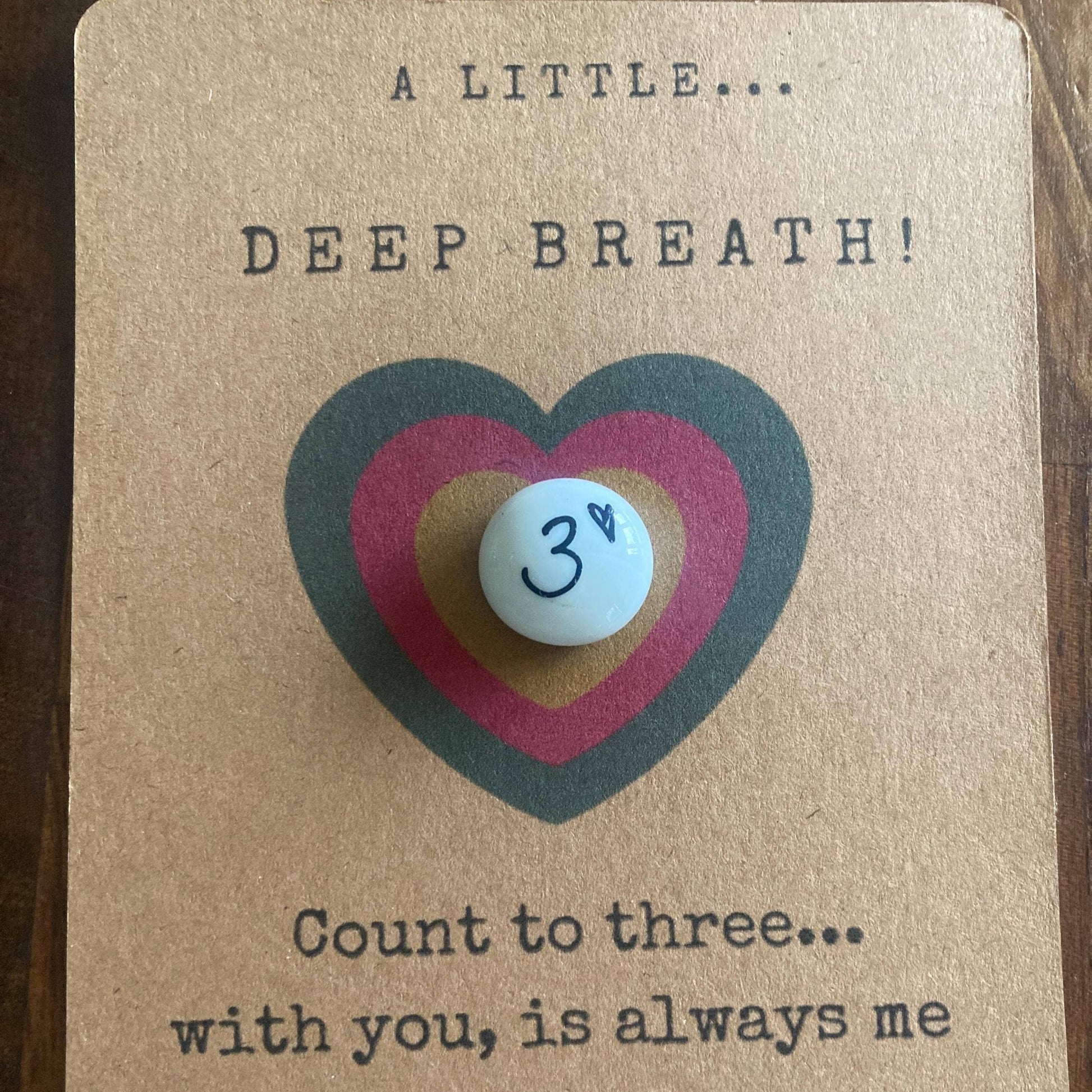 Card with a heart design and a small pebble, featuring text about taking deep breaths and connecting with someone.