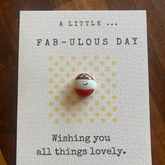 Card with a small round charm on a wooden surface