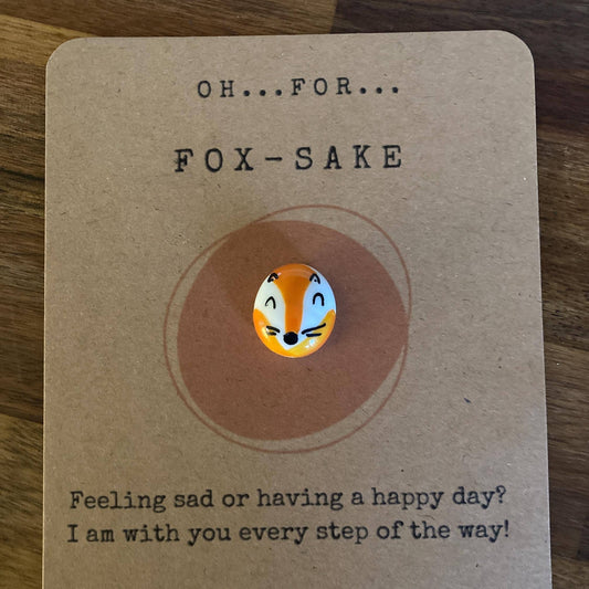 Card with a fox-themed pin and text on a wooden surface