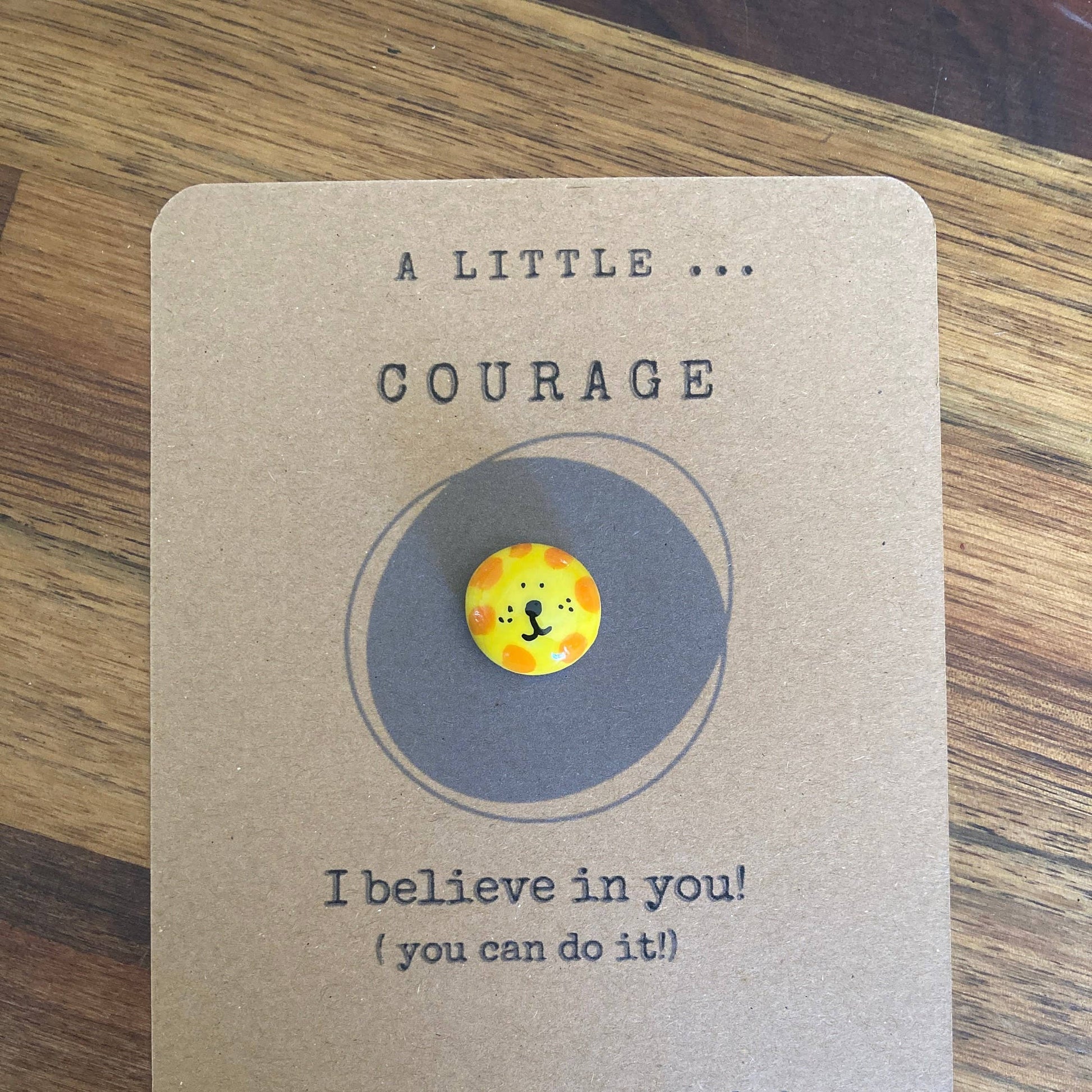 Motivational card with a token featuring a lion illustration on a wooden surface