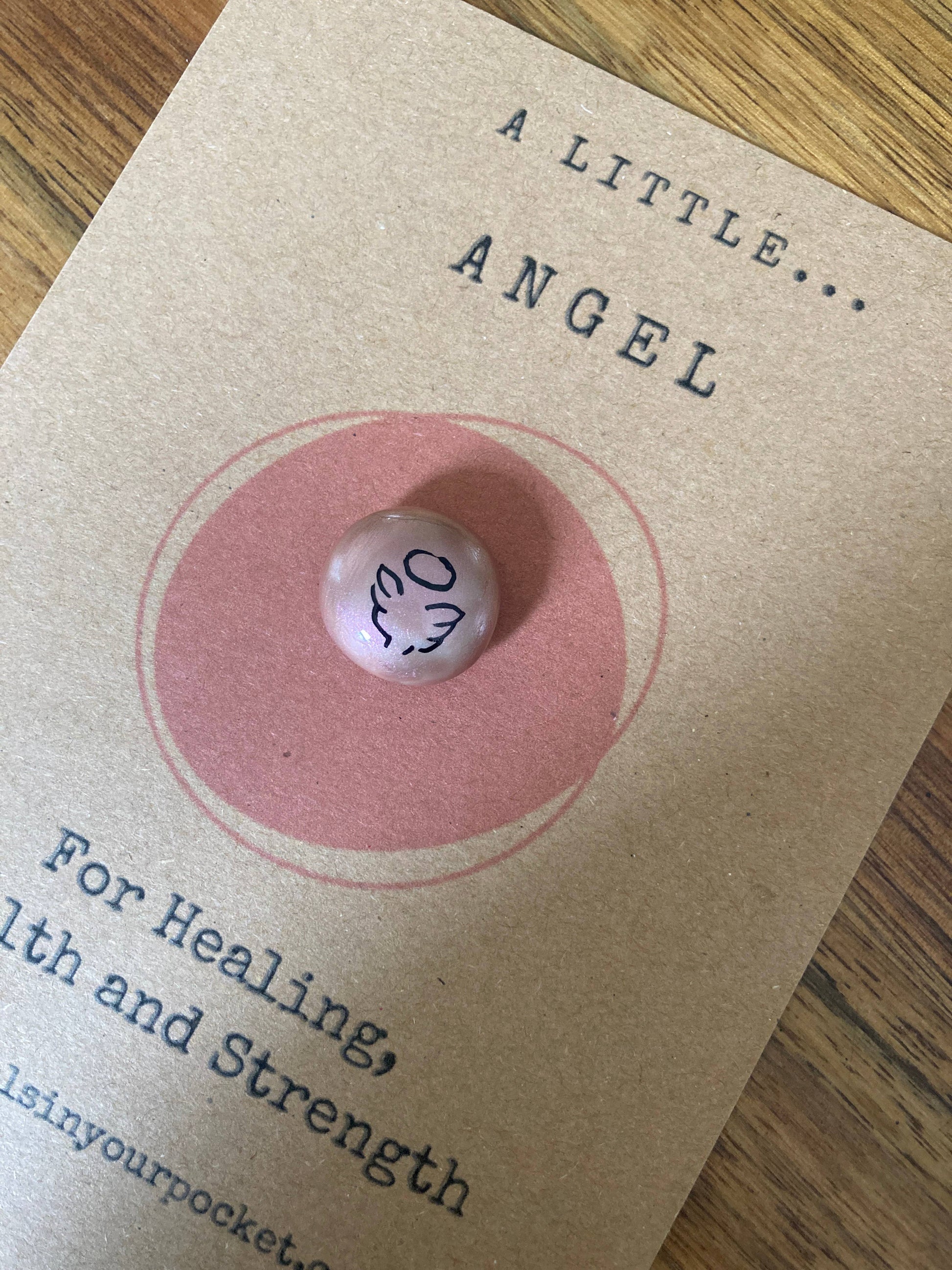 Pink angel token on a brown card with text