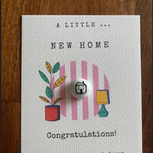 Greeting card with 'A Little New Home' text and illustrations on a wooden surface