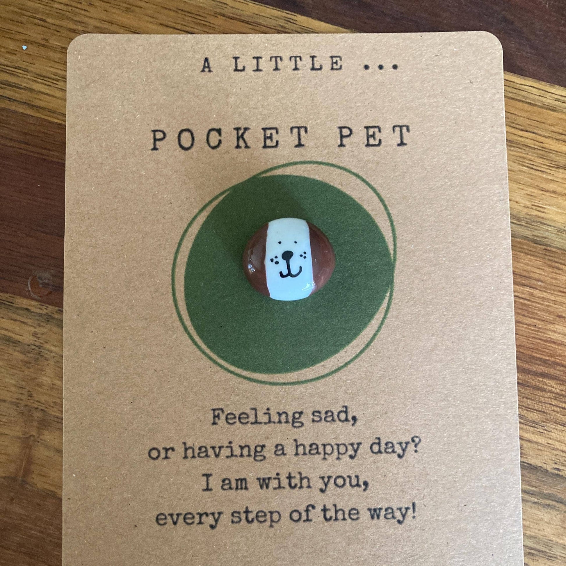 Pocket pet charm on a card with text on a wooden surface