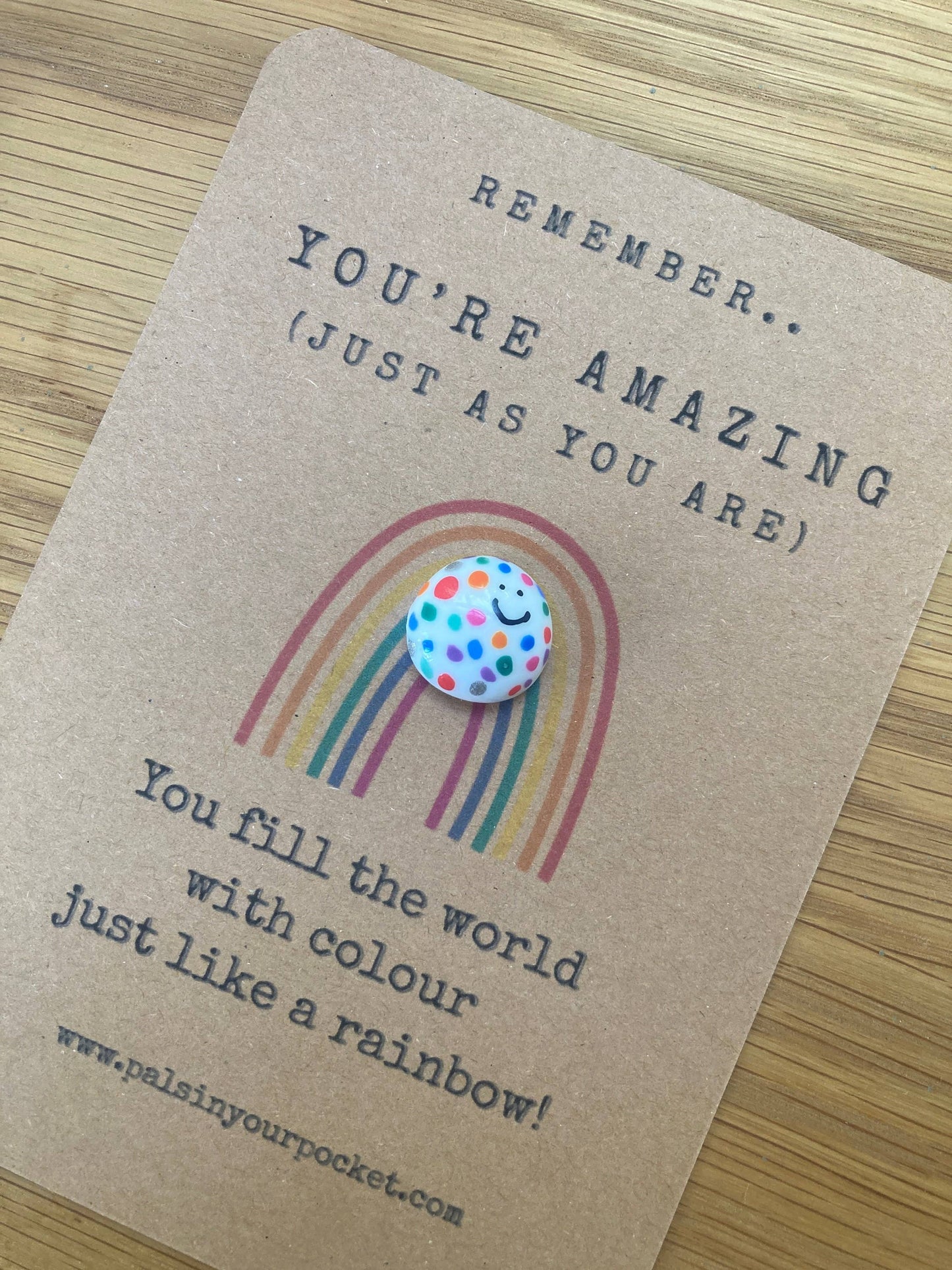 Card with a rainbow and polka dot token on a wooden surface