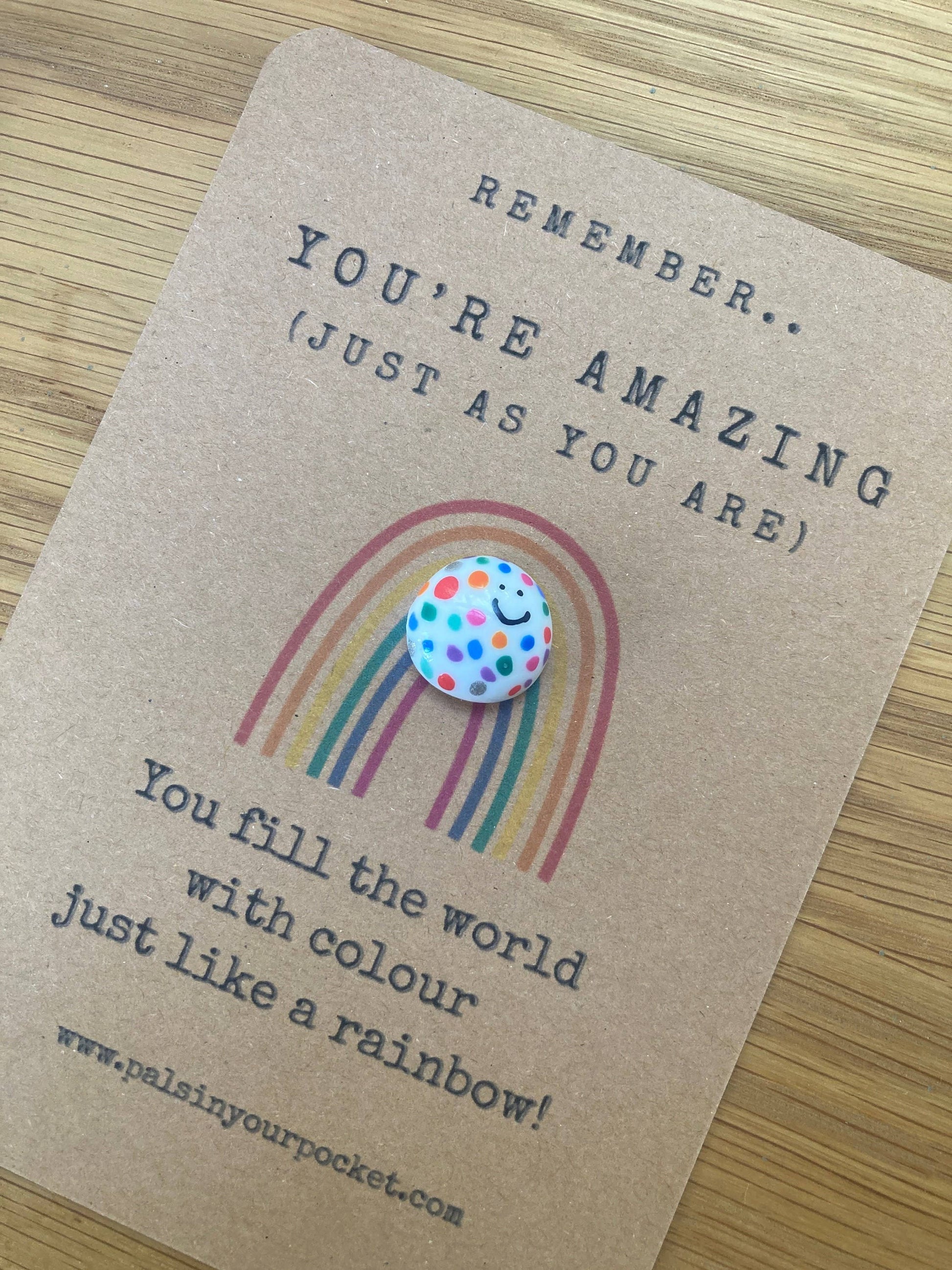 Card with a rainbow and polka dot token on a wooden surface