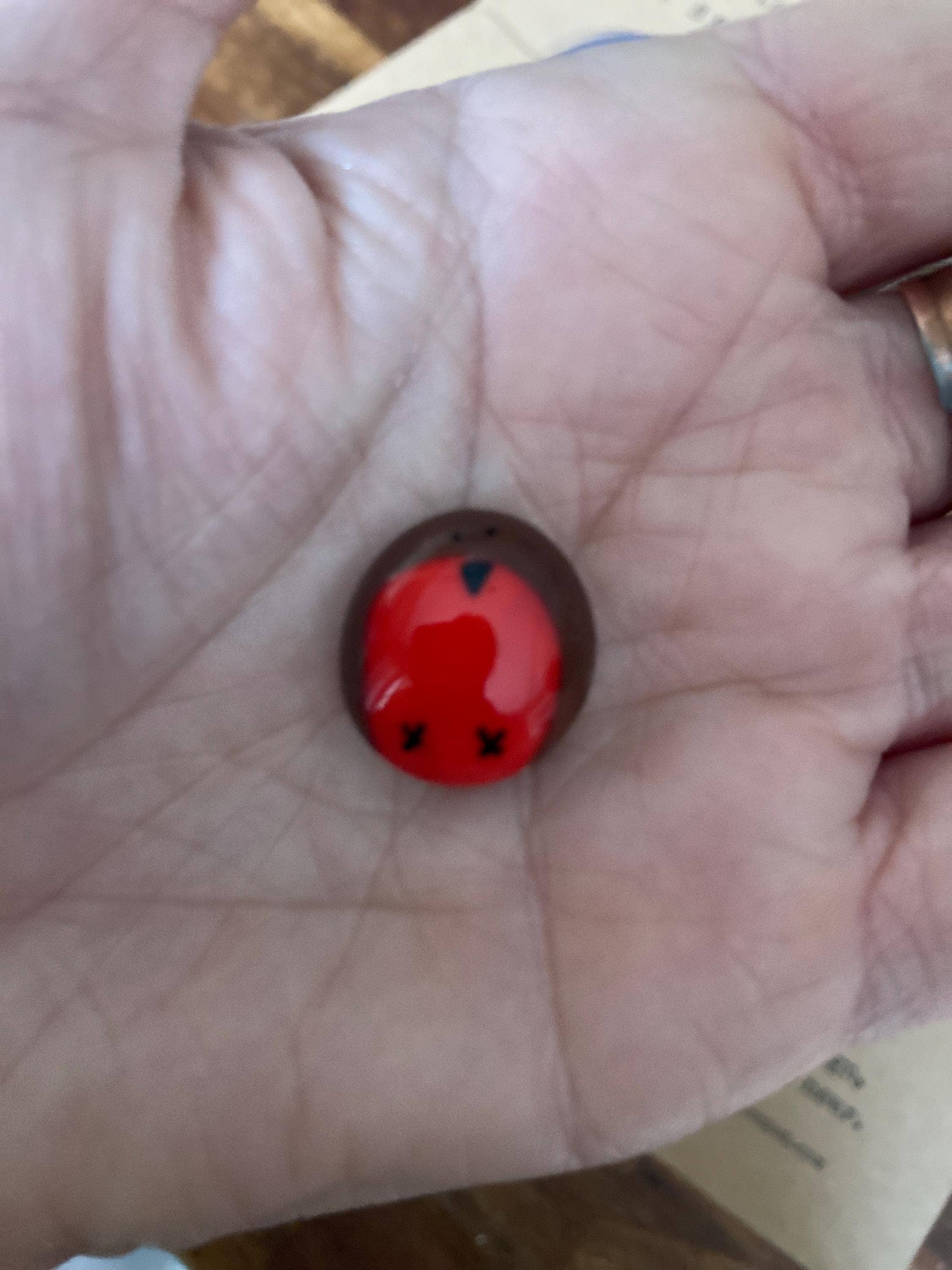 Small red robin with black details on a person's palm