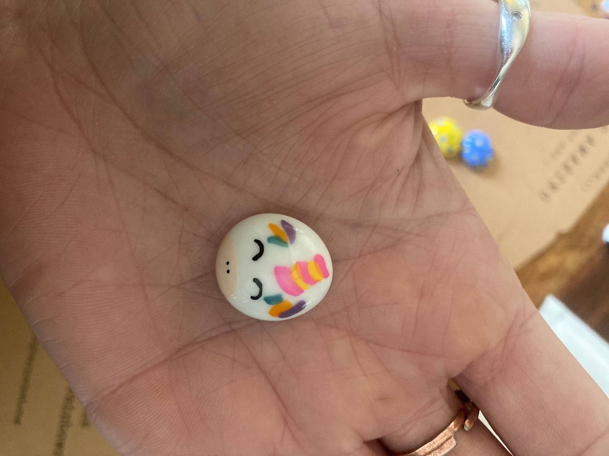Colorful button with smiley face design held in a hand
