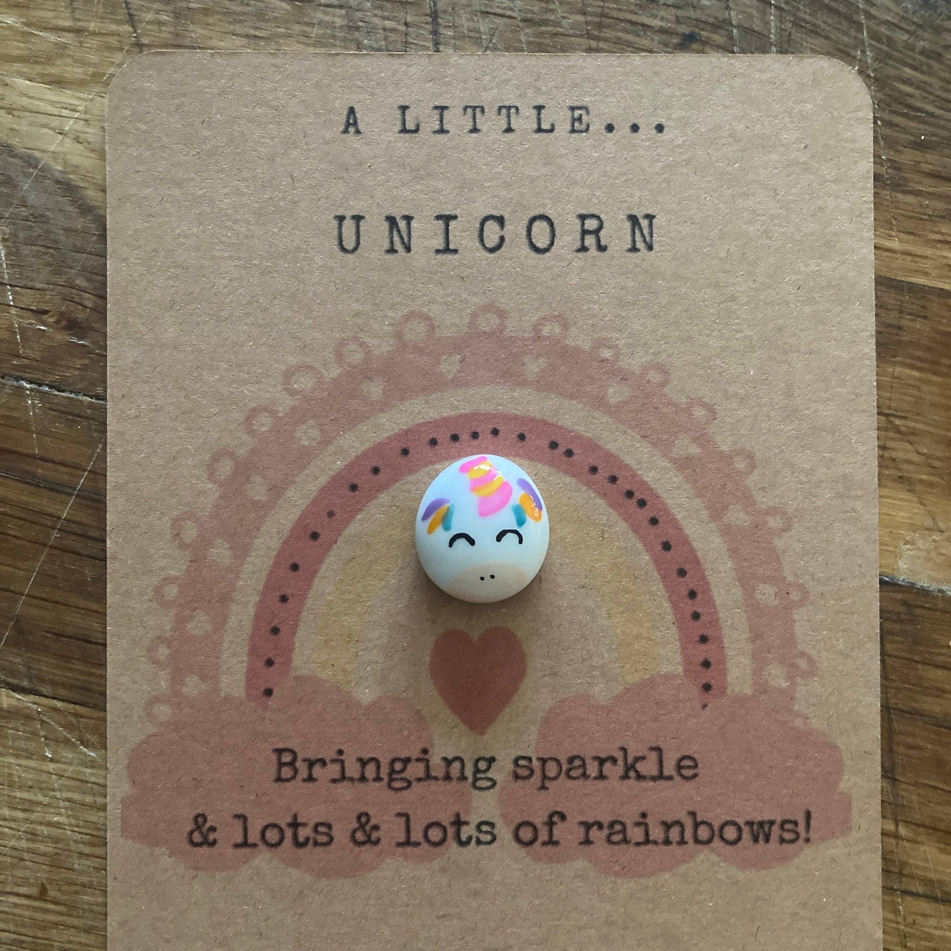 Unicorn-themed token on a brown card with text on a wooden surface