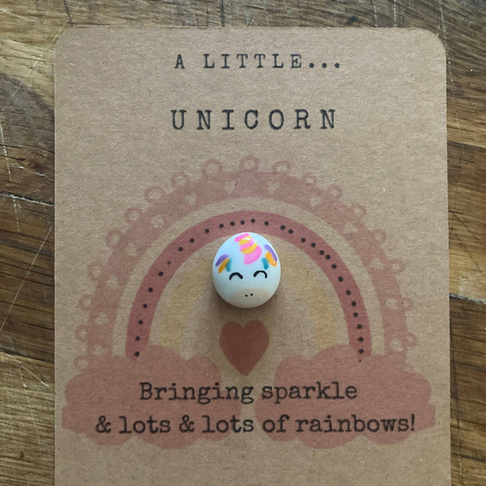 Unicorn-themed token on a brown card with text on a wooden surface