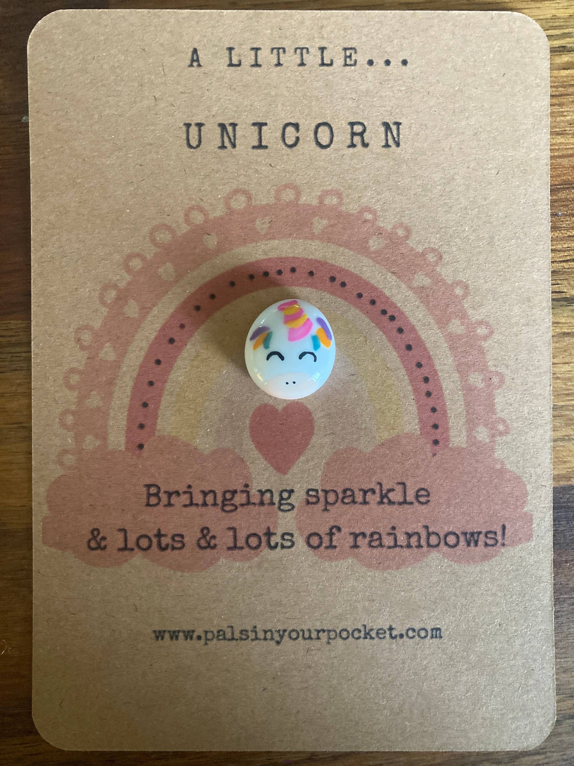 Unicorn charm on a kraft paper card with text and rainbow design