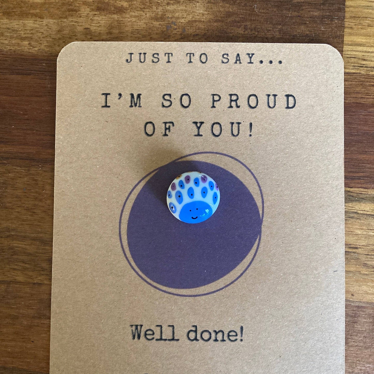 Motivational card with peacock print design on a wooden surface