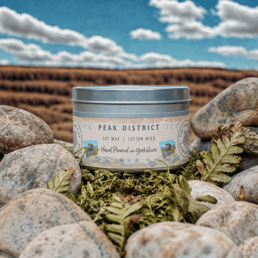 Candle jar labeled 'Peak District' on stones with a natural background