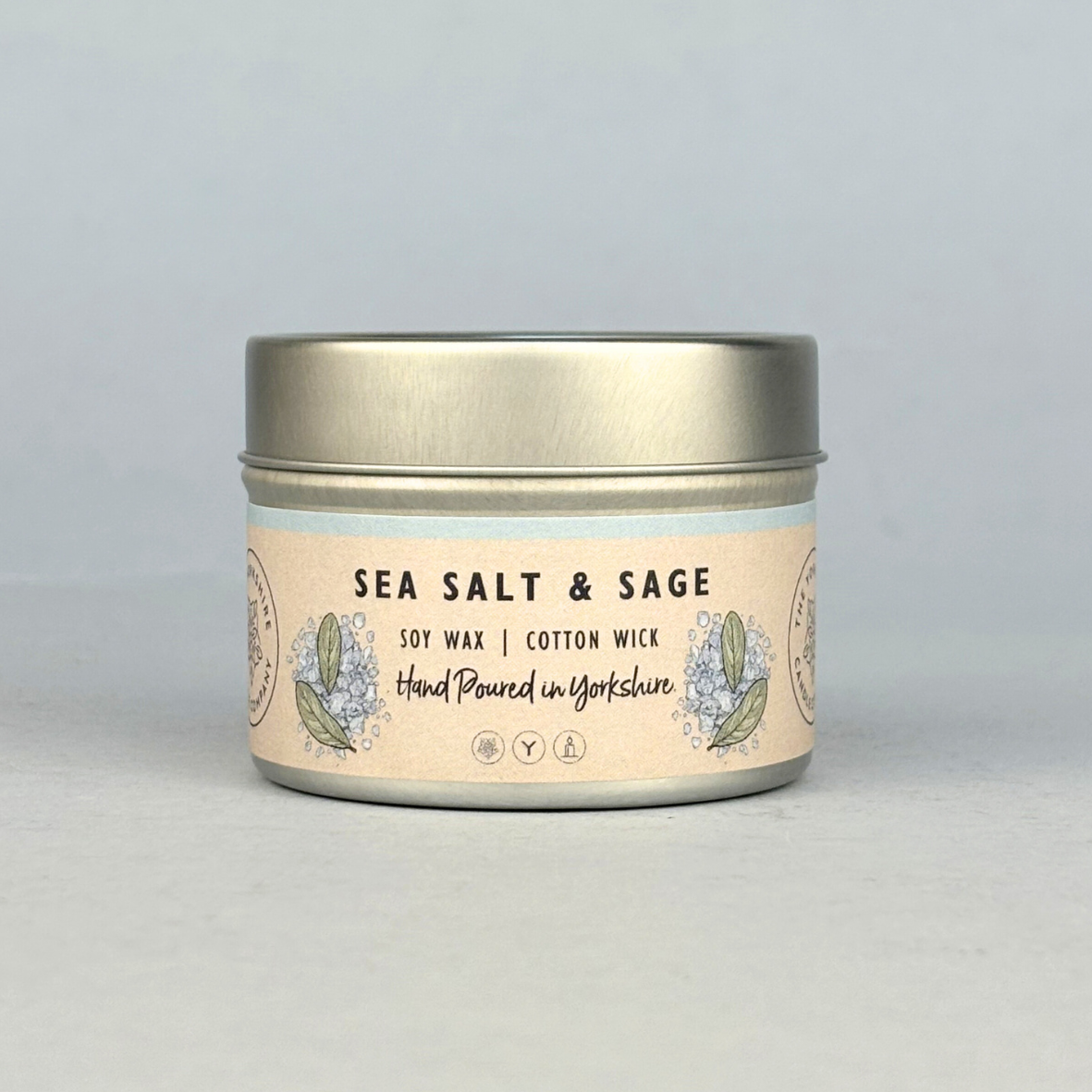 Candle tin labeled 'Sea Salt & Sage' on a light gray background