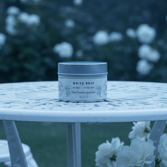 Candle in a tin labeled 'White Rose' on a light gray background
