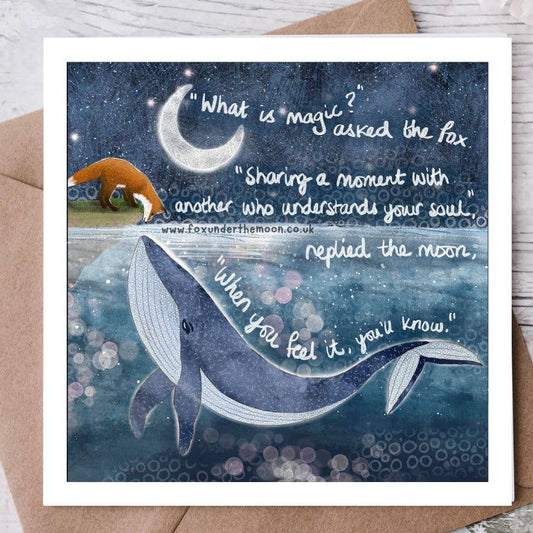Greeting card with whale illustration and moon, featuring a quote on a wooden surface.
