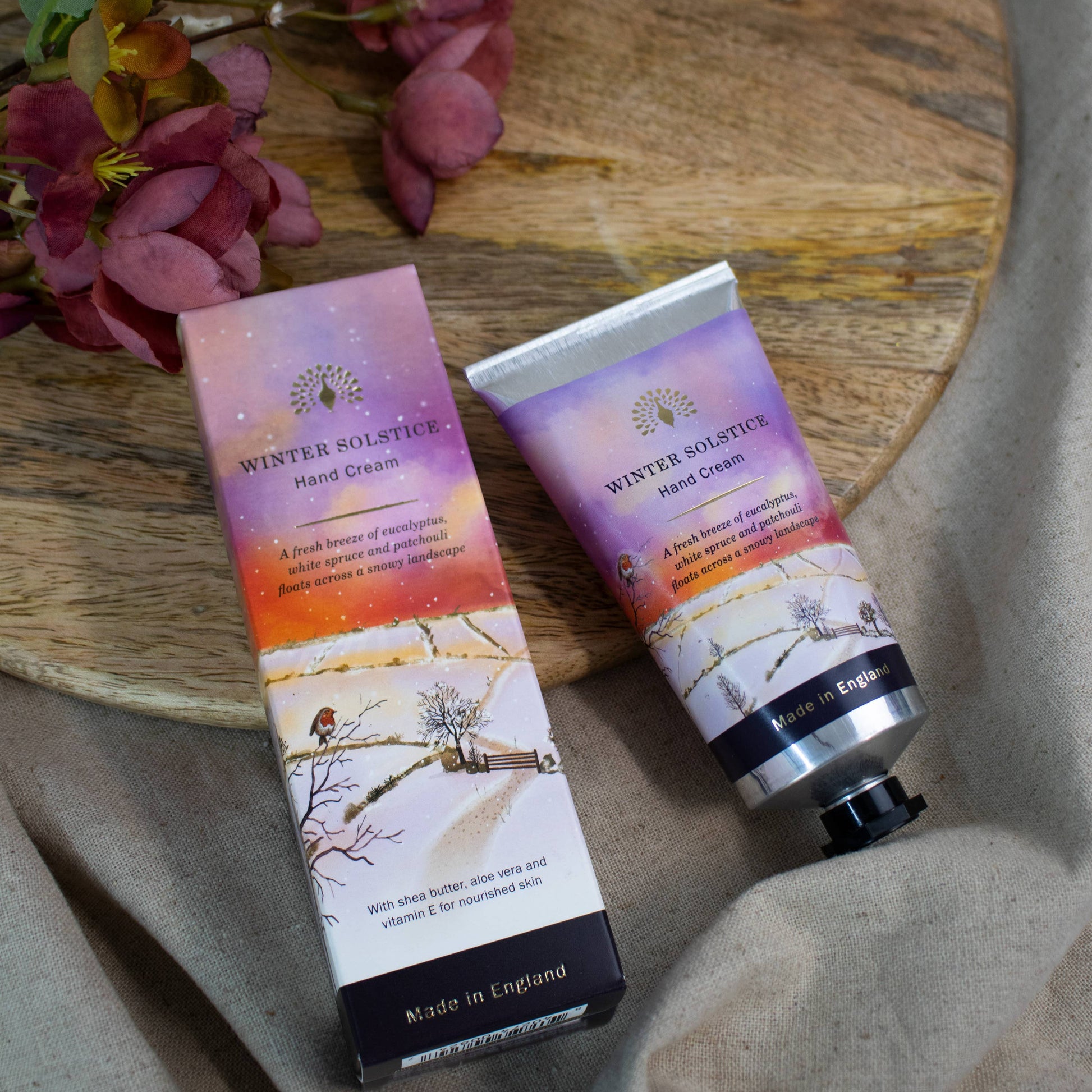 Hand cream and packaging on a wooden board with flowers