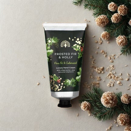 Hand cream tube labeled 'Frosted Fir & Holly' with decorative elements on a light background
