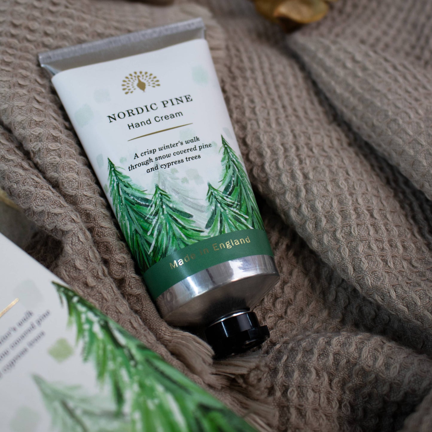 Hand cream with a green label on a textured fabric surface