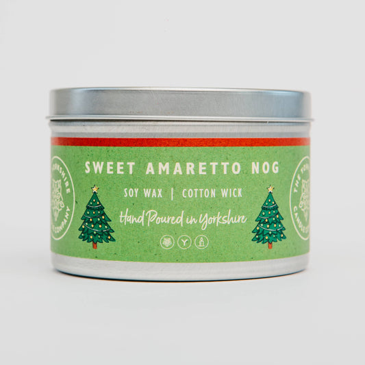 Candle tin labeled 'Sweet Amaretto Nog' with green and red design on a white background