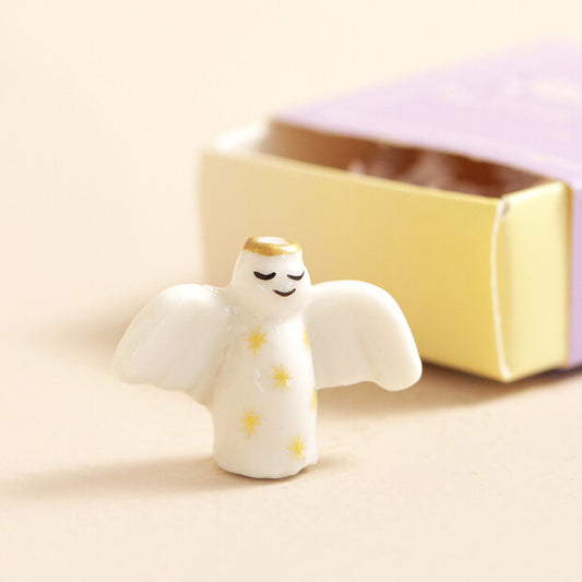 Small angel figurine with a gold halo on a beige background