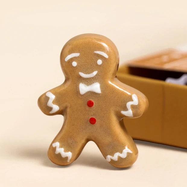 Gingerbread man cookie with a bow tie and red buttons on a beige background