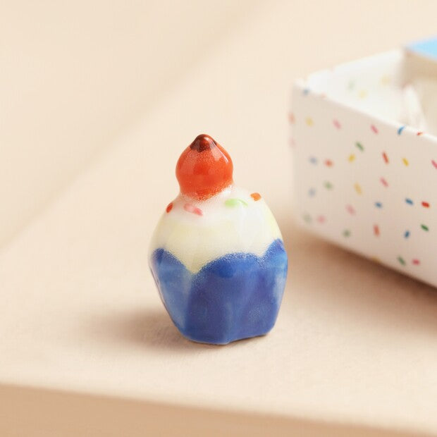 Small ceramic ornament with blue and white design on a beige background
