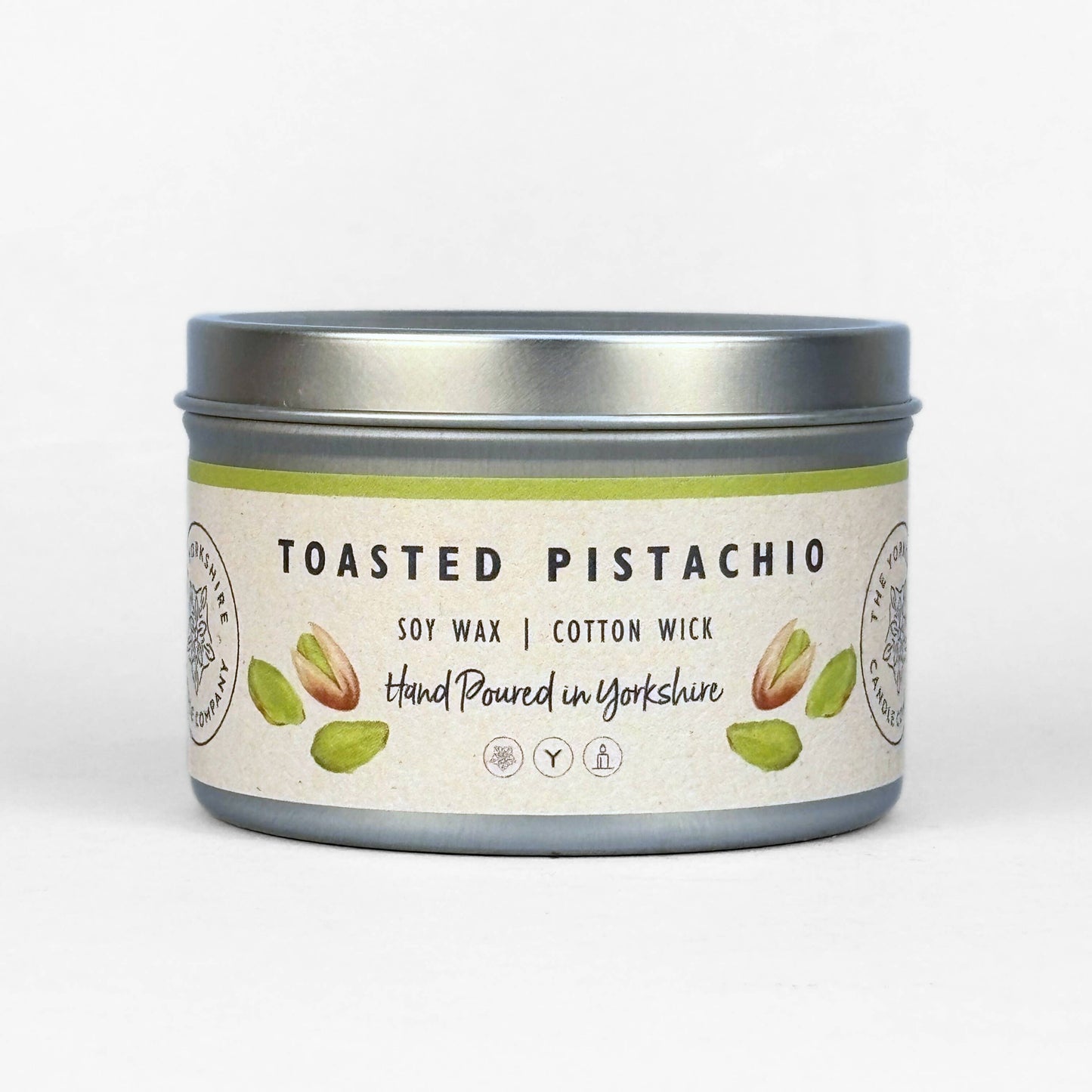 Candle in a tin labeled 'Toasted Pistachio' on a white background