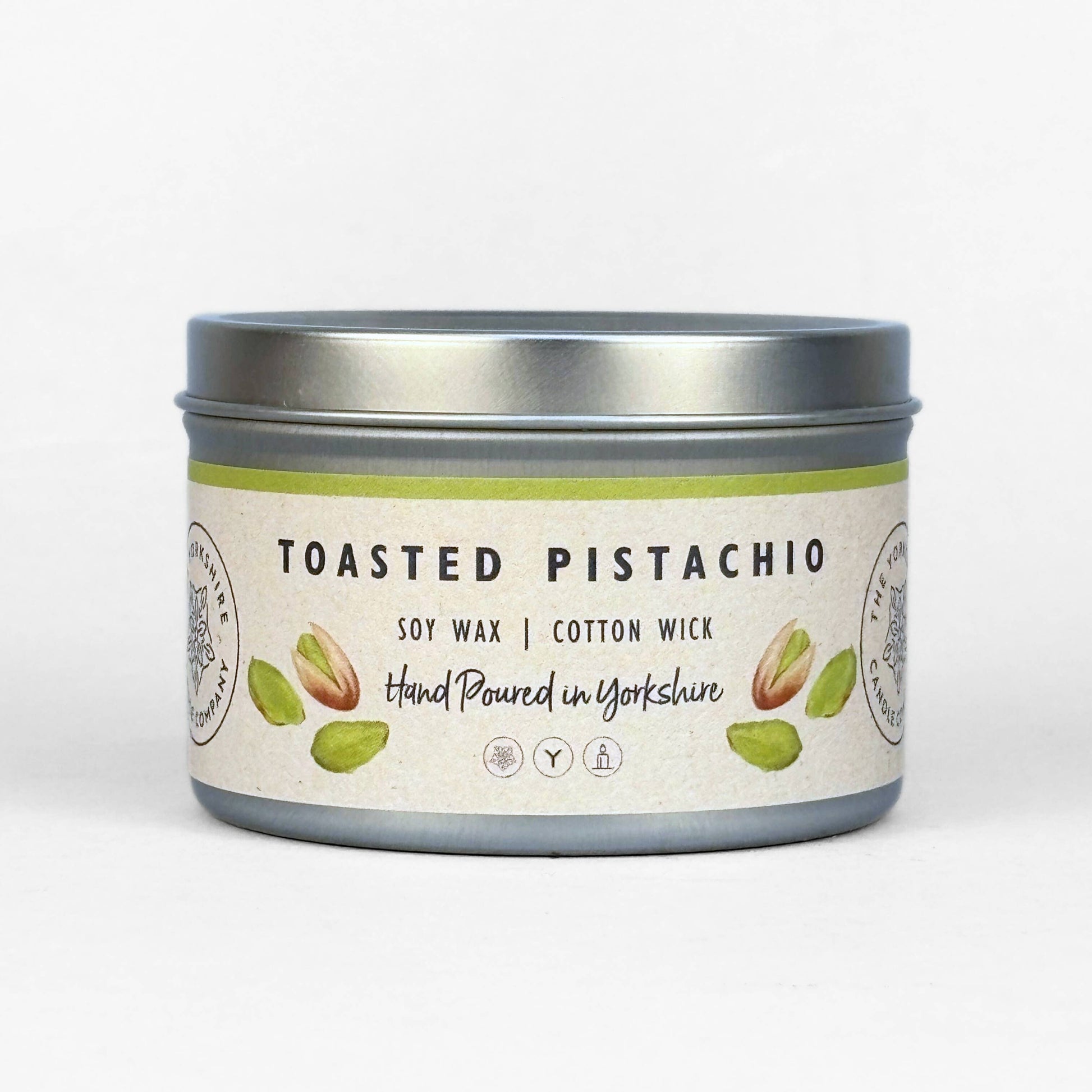 Candle in a tin labeled 'Toasted Pistachio' on a white background
