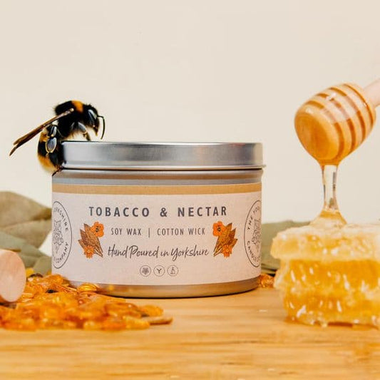 Candle labeled 'Tobacco & Nectar' with a bee and honeycomb on a wooden surface