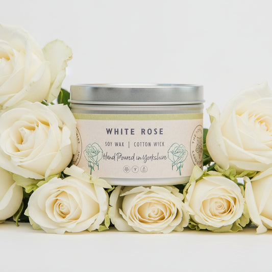 Candle tin labeled 'White Rose' with soy wax and cotton wick 