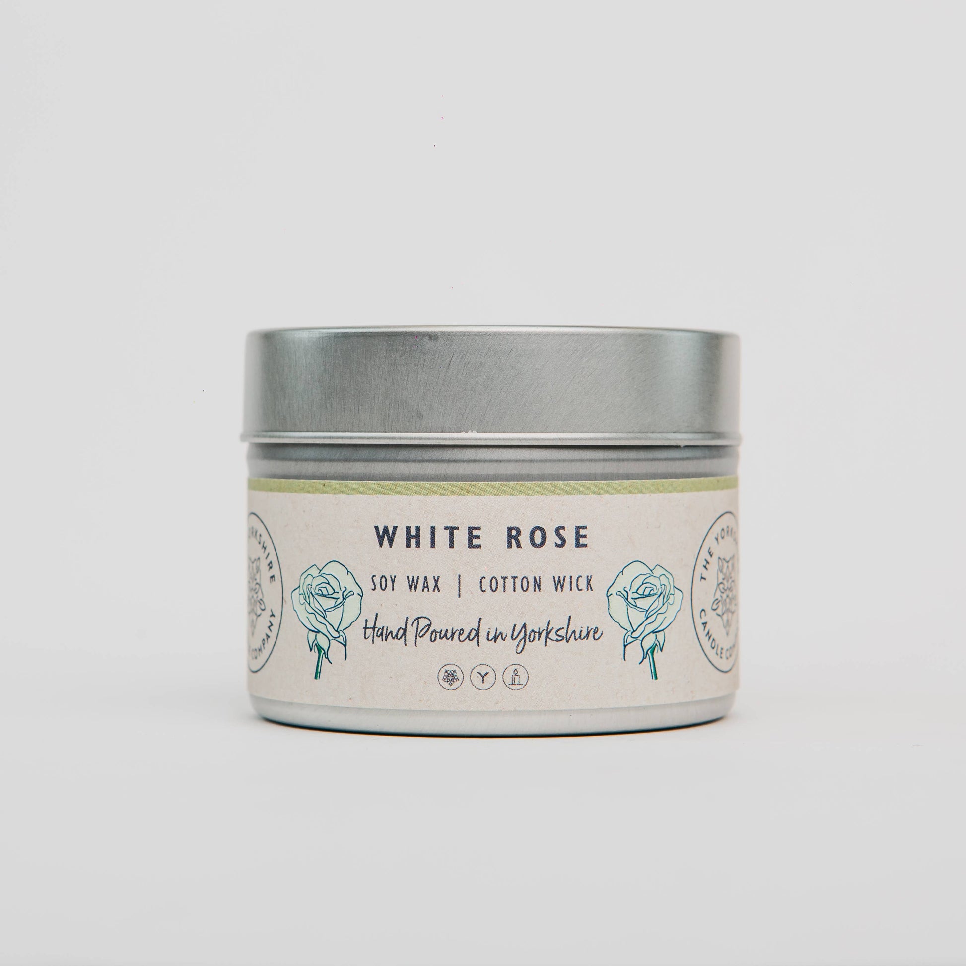 Candle in a tin labeled 'White Rose' on a light gray background