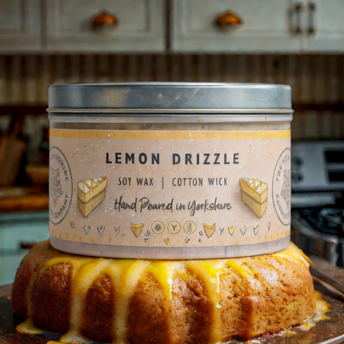 Lemon drizzle candle in a tin with a cake on a kitchen counter