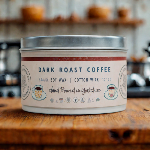 Dark roast coffee candle in a tin on a wooden surface with a blurred kitchen background